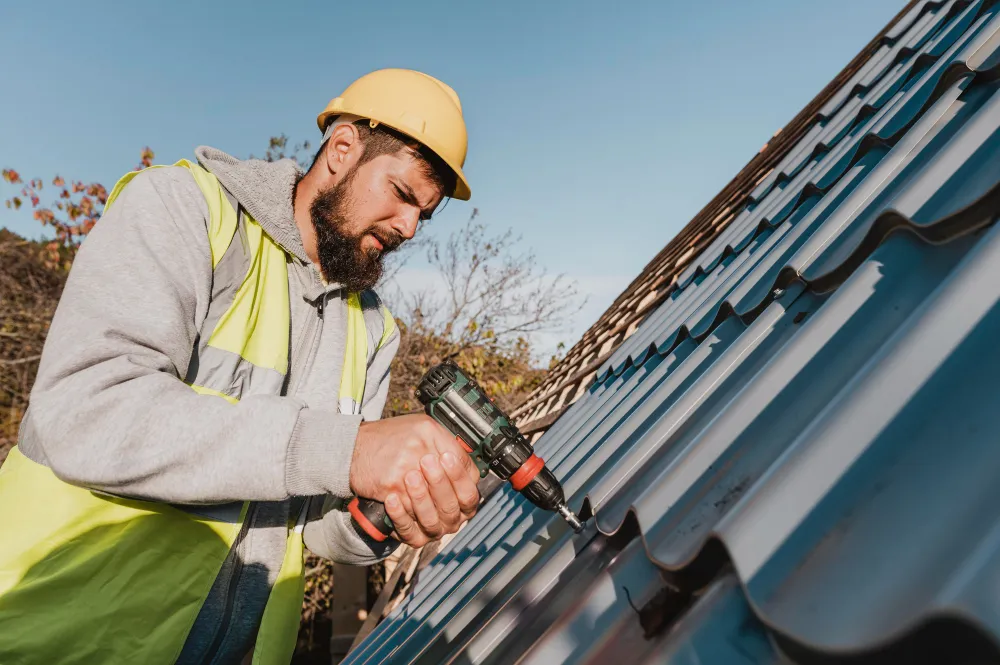 Roofing contractor securing metal tile roof panels with a power drill